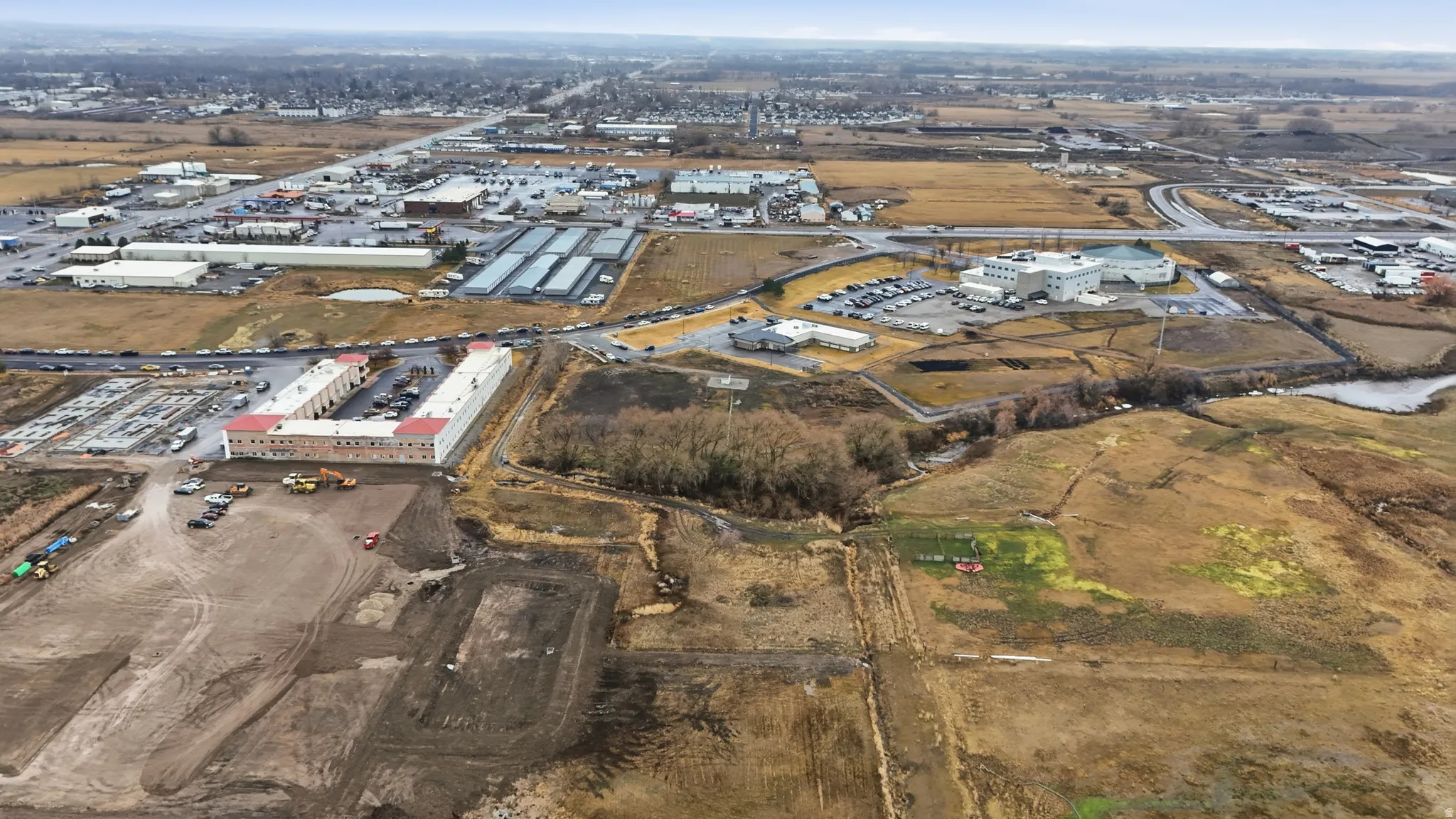 Expansive aerial view showcasing commercial properties, including a U-shaped building with a central parking area and multiple smaller structures