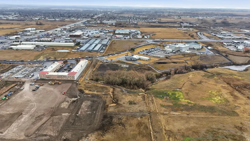 Expansive aerial view showcasing commercial properties, including a U-shaped building with a central parking area and multiple smaller structures