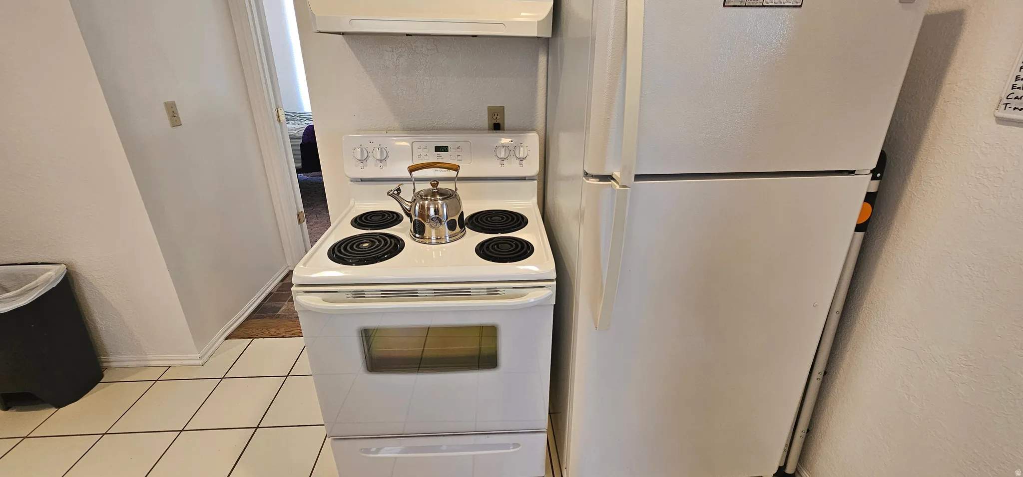 Kitchen area featuring tile flooring, a white electric range, and a white refrigerator
