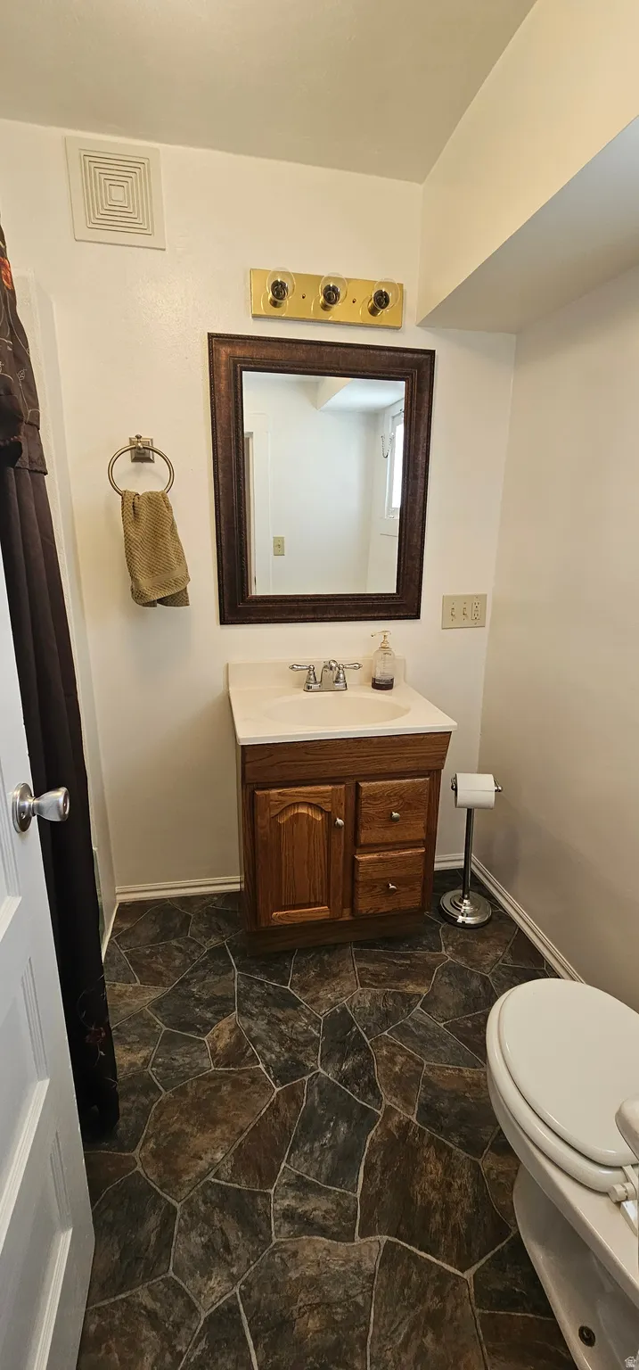Bathroom featuring a wood-finish vanity with a single basin sink and a framed mirror