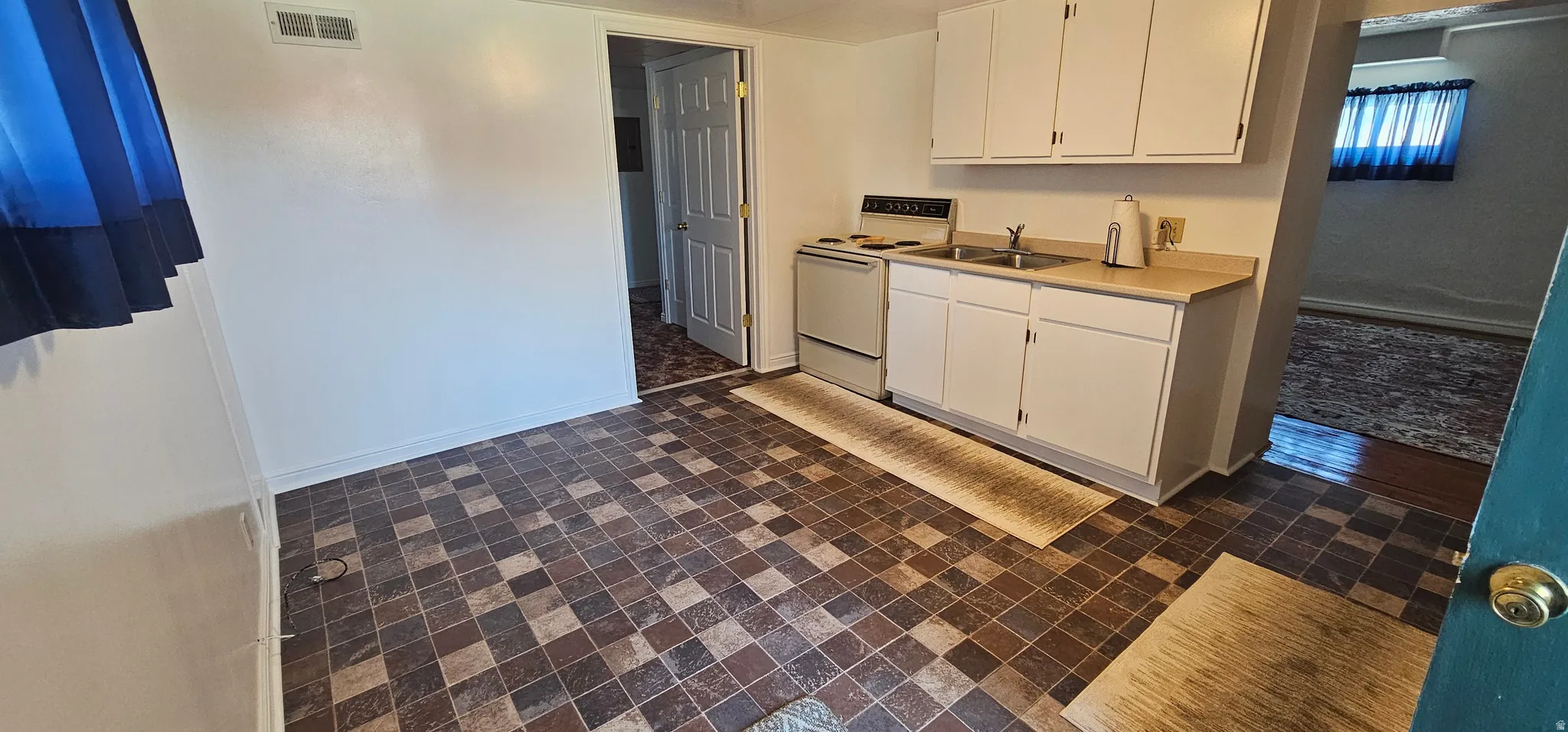 Kitchen area featuring checkered pattern flooring and white cabinetry