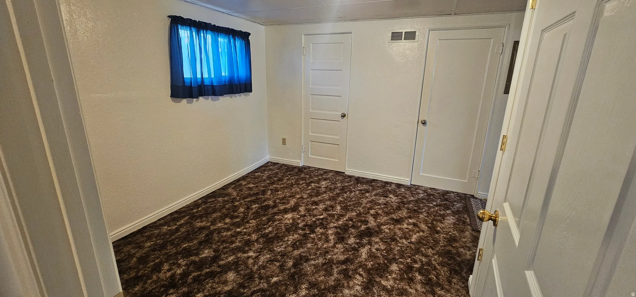 Room featuring brown patterned carpeting, white painted walls, and white trim