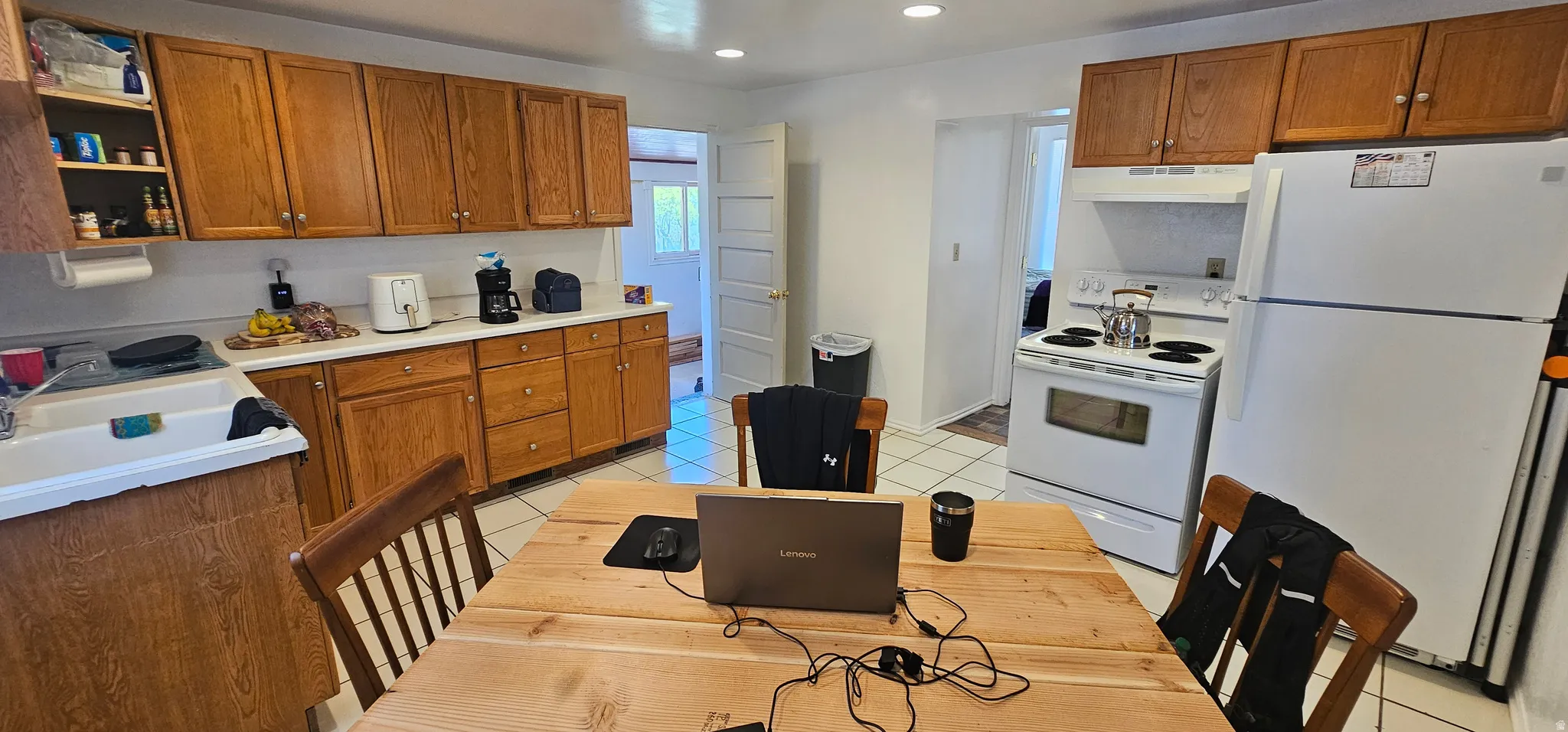 Kitchen featuring wood cabinetry, white countertops, white tile flooring, and white appliances