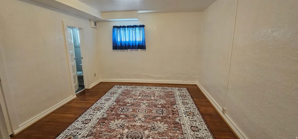 Room with wood-finish flooring, light-toned walls, and white baseboards