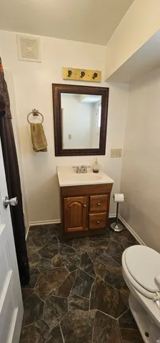 Bathroom featuring a wood-finish vanity with a single basin sink and a framed mirror