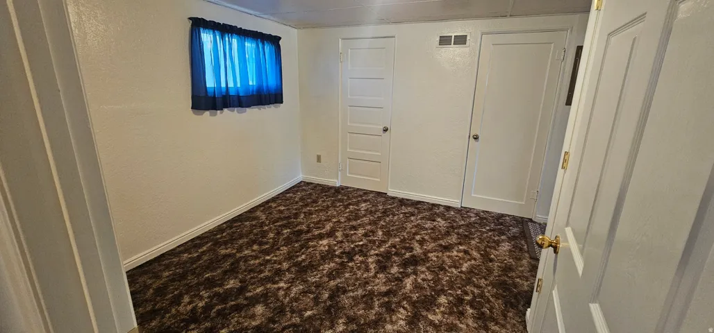 Room featuring brown patterned carpeting, white painted walls, and white trim