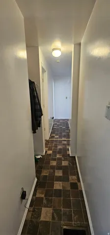 Hallway featuring checkerboard tile-look flooring and white baseboards