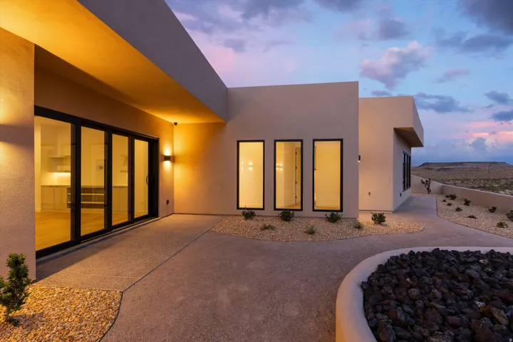 Modern exterior with a stucco finish, multi-panel sliding glass doors, and a concrete patio