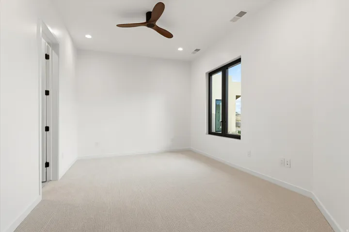 Spacious room featuring light-colored carpeting, a contemporary ceiling fan, and recessed lighting