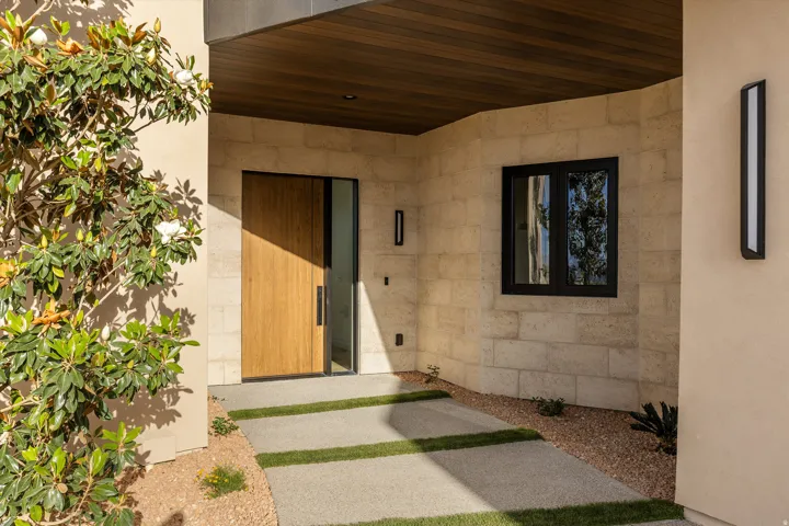 Modern entryway featuring a light wood-finish pivot door with a vertical pull handle, complemented by a sidelite