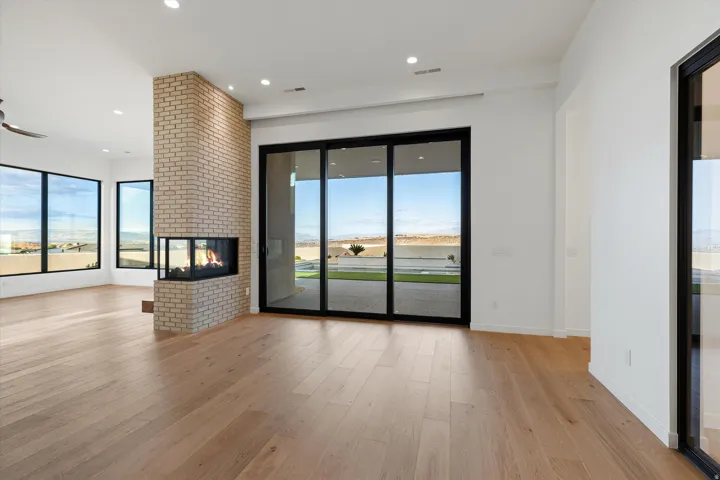 Light wood-finish flooring complements a floor-to-ceiling brick fireplace with a three-sided hearth