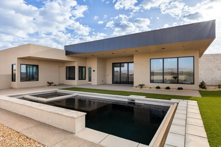 Contemporary exterior featuring a rectangular pool with an integrated spa, expansive patio area, and low-maintenance artificial turf