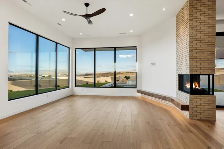 Expansive room with natural wood-finish flooring and a contemporary ceiling fan