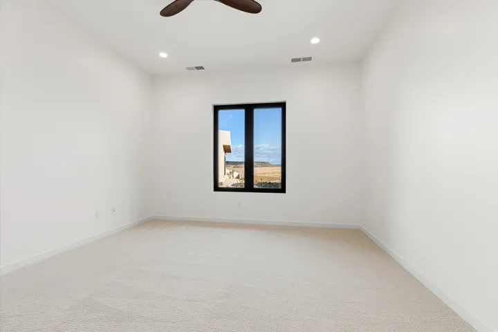 Spacious room featuring a large black-framed window, recessed lighting, and light-toned carpeting