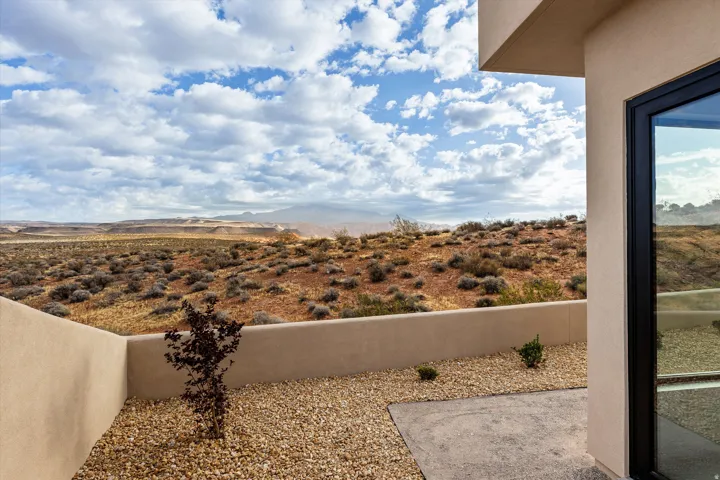 Outdoor patio area with desert landscaping, a low retaining wall, and a broad expanse of distant mountains
