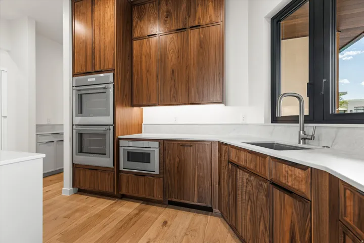 Kitchen featuring rich wood-finish cabinetry, light stone countertops, and wood-finish flooring