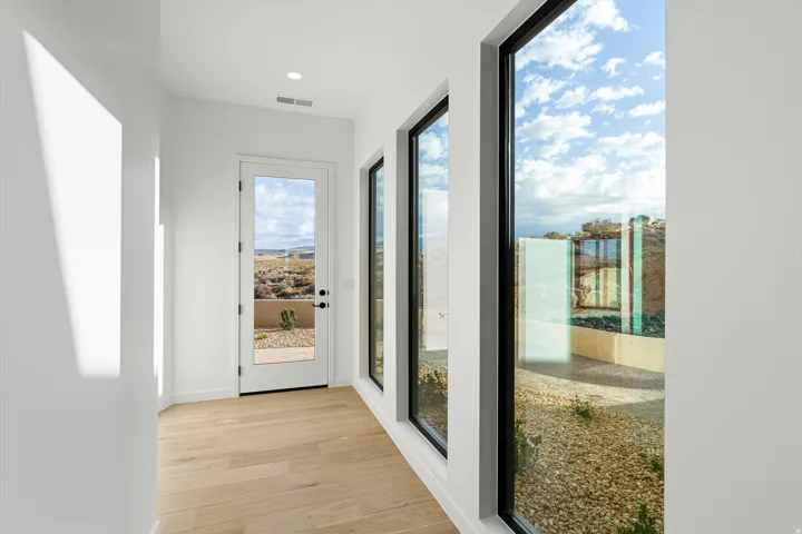 Light wood-finish flooring extending through a hallway with white walls