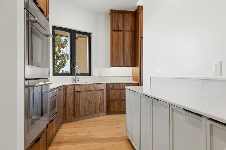Contemporary kitchen featuring light wood-finish flooring, white countertops, and a built-in stainless steel oven