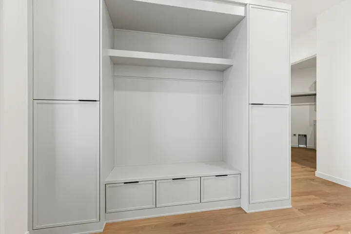 Custom built-in storage unit with light-toned cabinetry, integrated seating, and multiple drawers