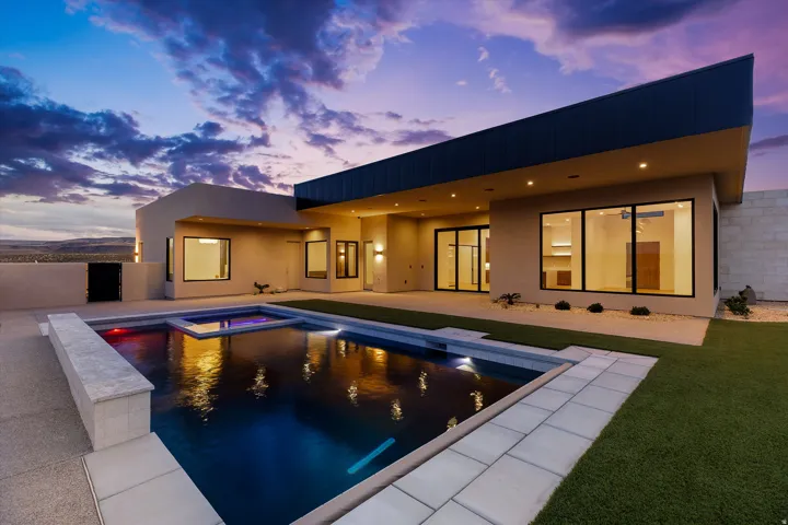 Contemporary exterior with flat roofline, showcasing an in-ground swimming pool, integrated spa, and expansive patio
