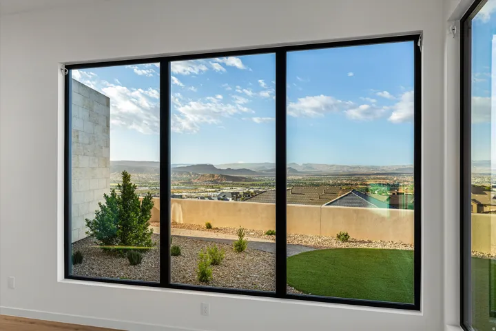 Expansive multi-panel window featuring black framing, showcasing a desert landscape with distant mountains
