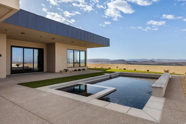 Outdoor living space featuring a rectangular swimming pool with an integrated spa, surrounded by textured concrete decking