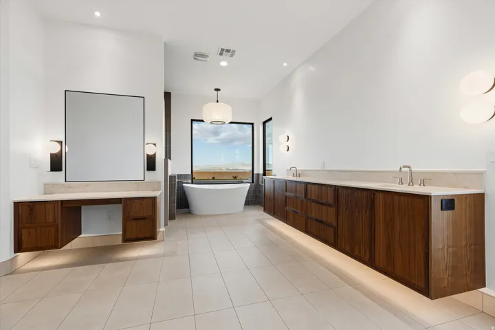 Spacious bathroom featuring a freestanding soaking tub, a large picture window, and a floating dual vanity with integrated sinks