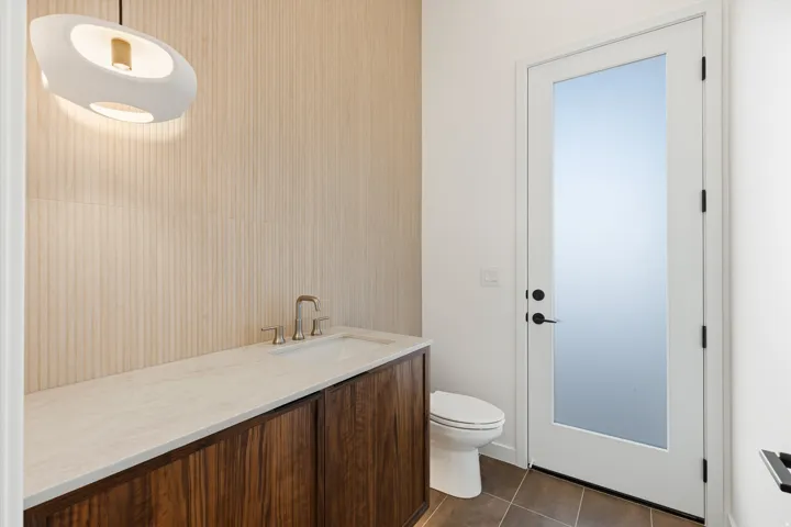 Modern vanity featuring a light-toned countertop, wood-finish cabinetry, and brushed nickel fixtures