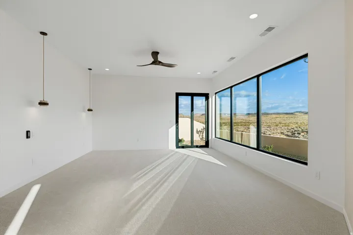 Expansive room featuring light-toned carpeting, a contemporary ceiling fan, and recessed lighting