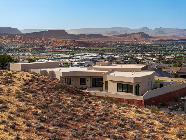 Contemporary stucco exterior with flat rooflines, dark-framed windows, and a red rock landscape backdrop