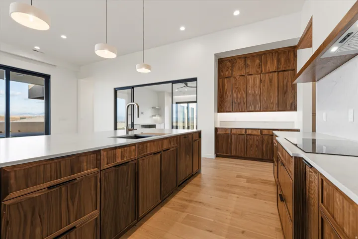 Modern kitchen with wood-finish cabinetry, white countertops, and light wood-finish flooring