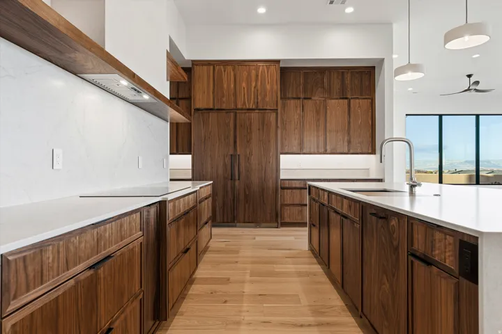 Kitchen featuring extensive dark wood cabinetry, light wood-finish flooring, and white countertops