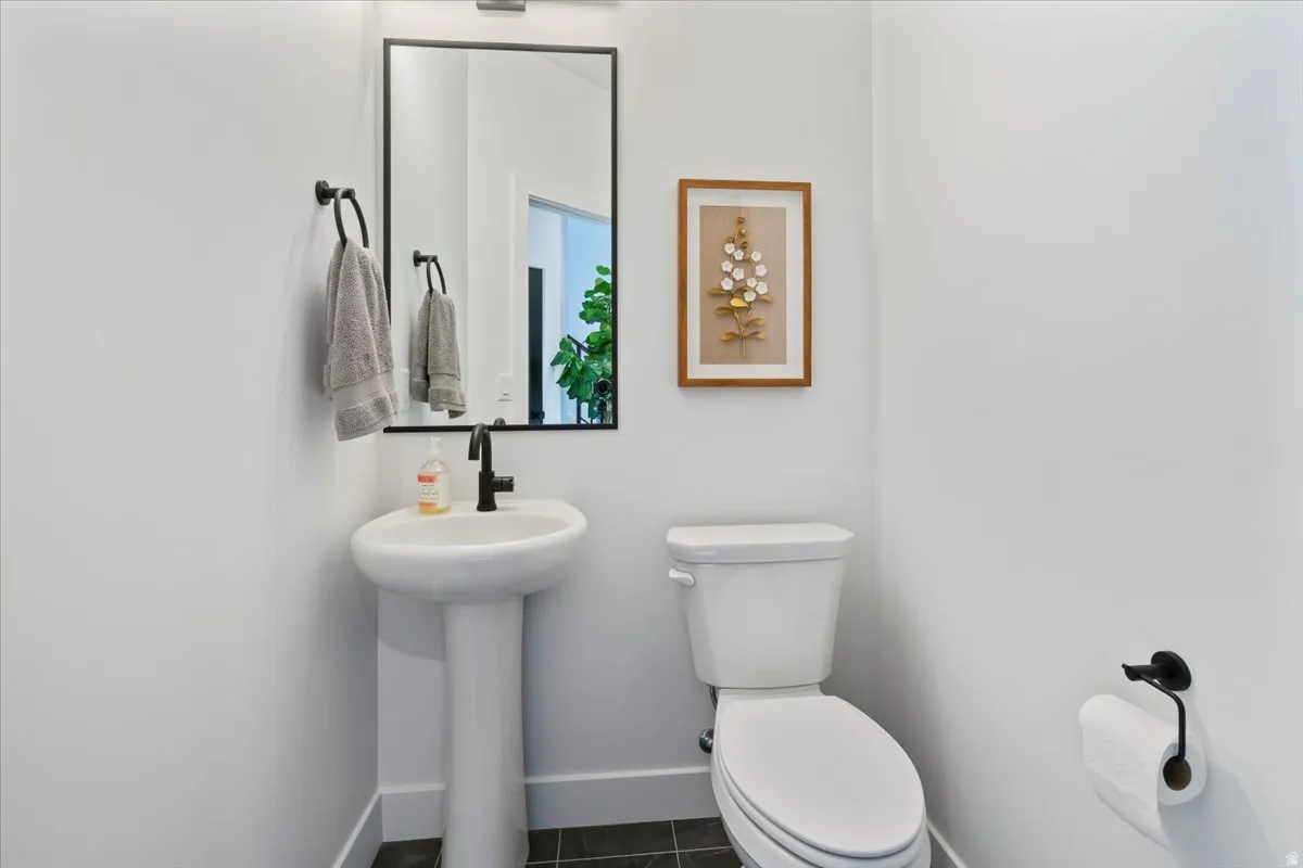 Pedestal sink with a matte black faucet and coordinating mirror