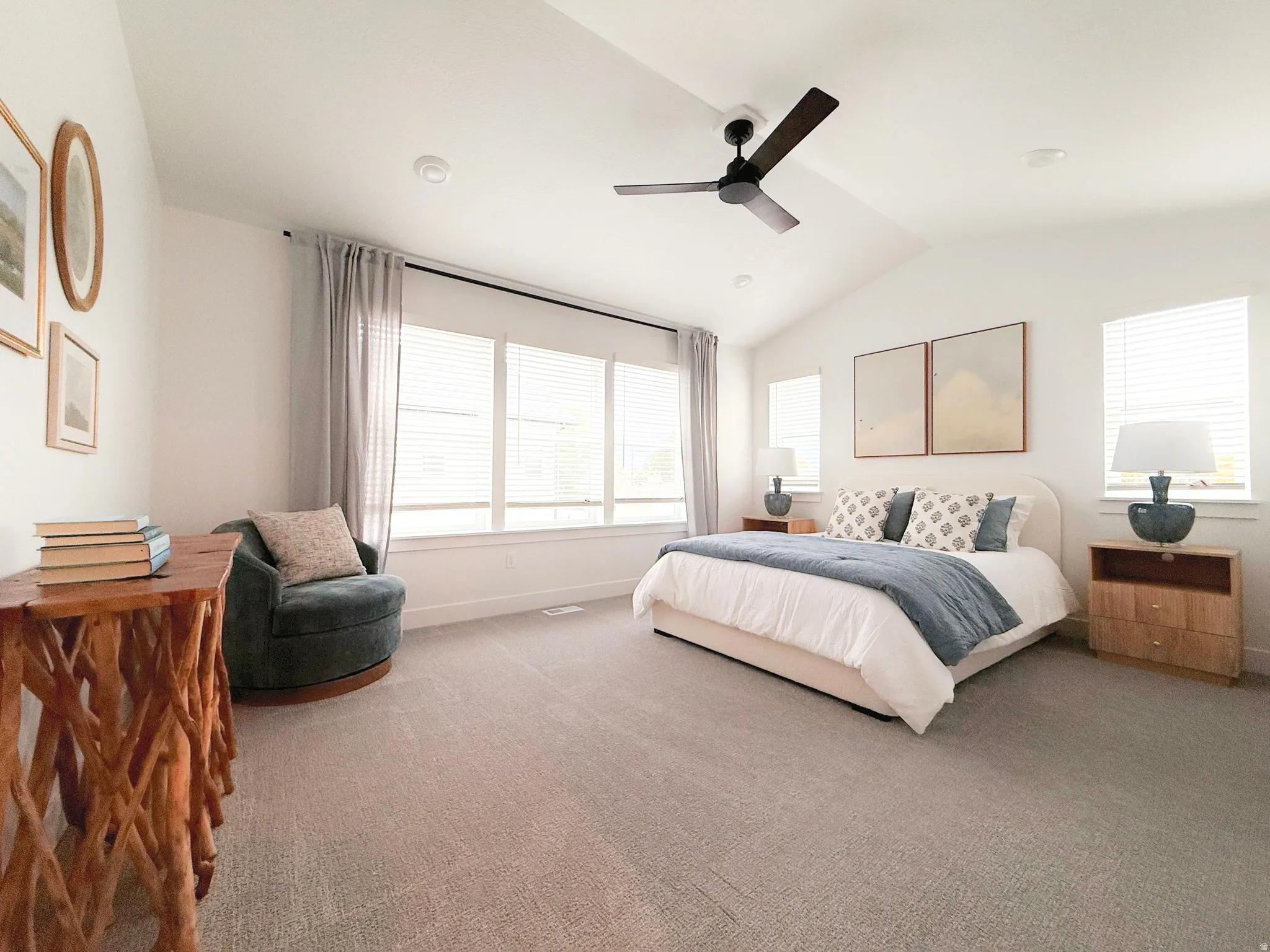 Vaulted ceilings featuring a ceiling fan, plush carpeting, and abundant natural light from multiple windows