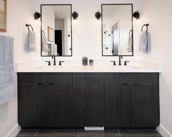 Dual vanity with dark wood-finish cabinetry, white countertop, and matte black fixtures