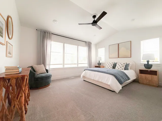 Vaulted ceilings featuring a ceiling fan, plush carpeting, and abundant natural light from multiple windows