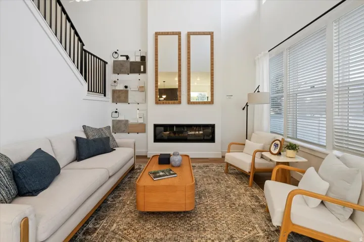 Spacious living area featuring a double-height ceiling, hardwood flooring, and a linear fireplace