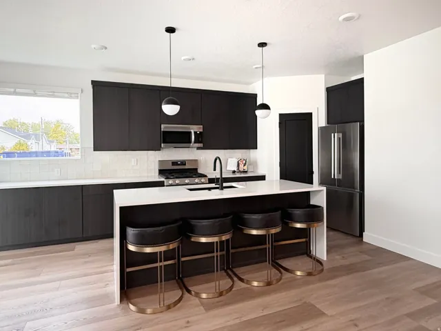 Modern kitchen featuring dark wood-finish cabinetry, stainless steel appliances, white tile backsplash, and a large central island with seating