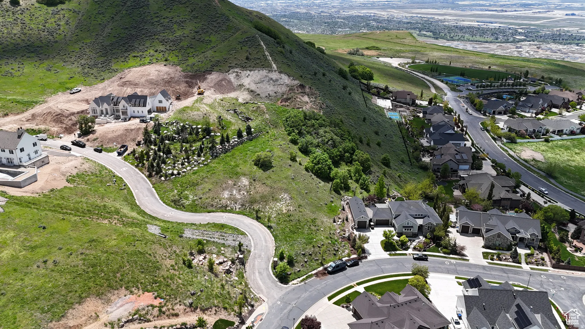 Hillside property featuring new construction homes, established residences, and a winding paved road
