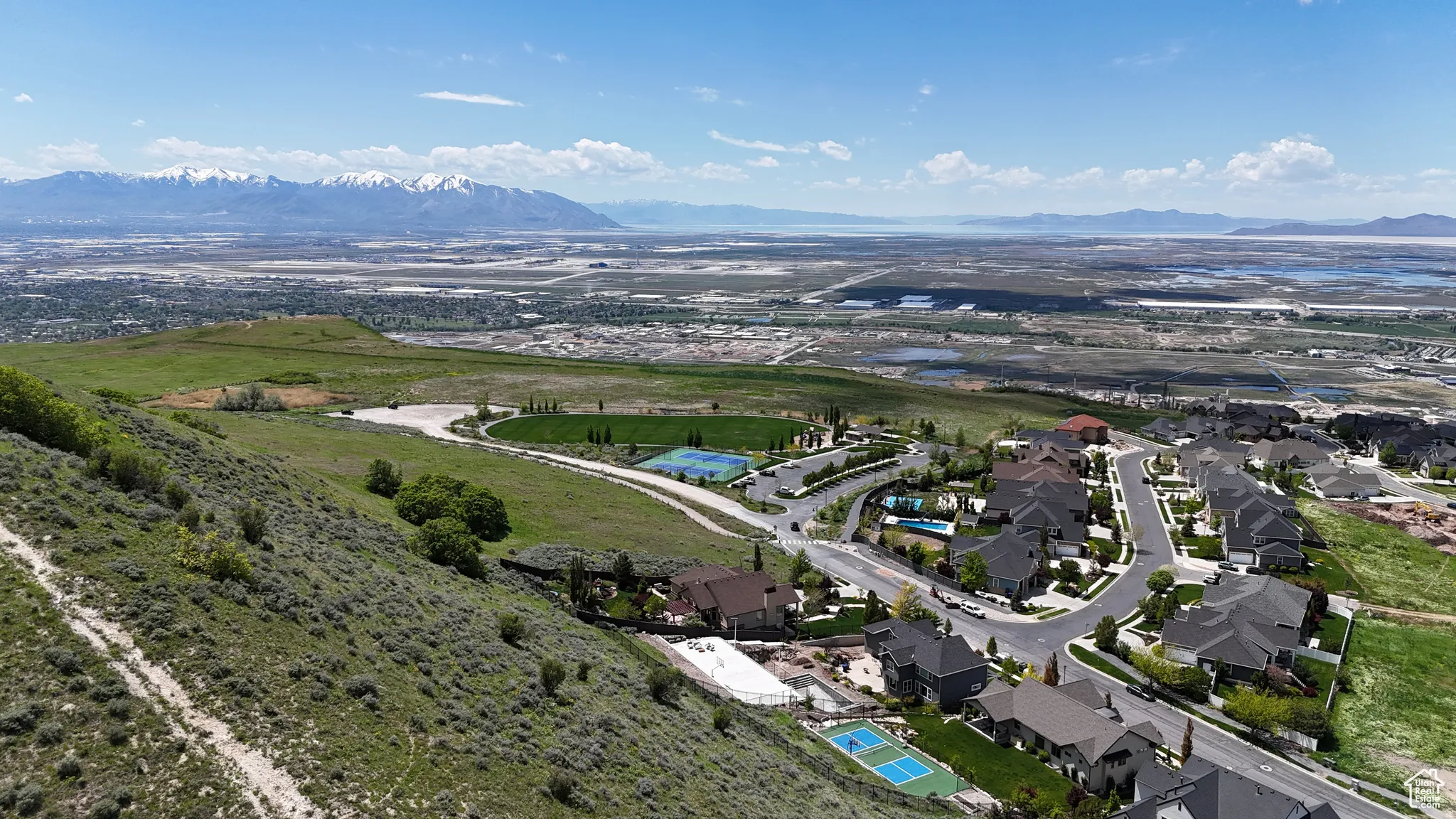 Expansive aerial view showcasing a residential neighborhood with custom homes, paved streets, and a mountainous backdrop