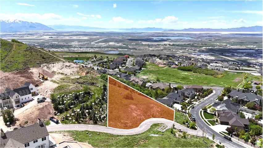Sloping hillside parcel with surrounding residential development and paved road frontage