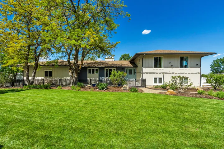 Expansive green lawn bordering the property, featuring mature trees and landscaping