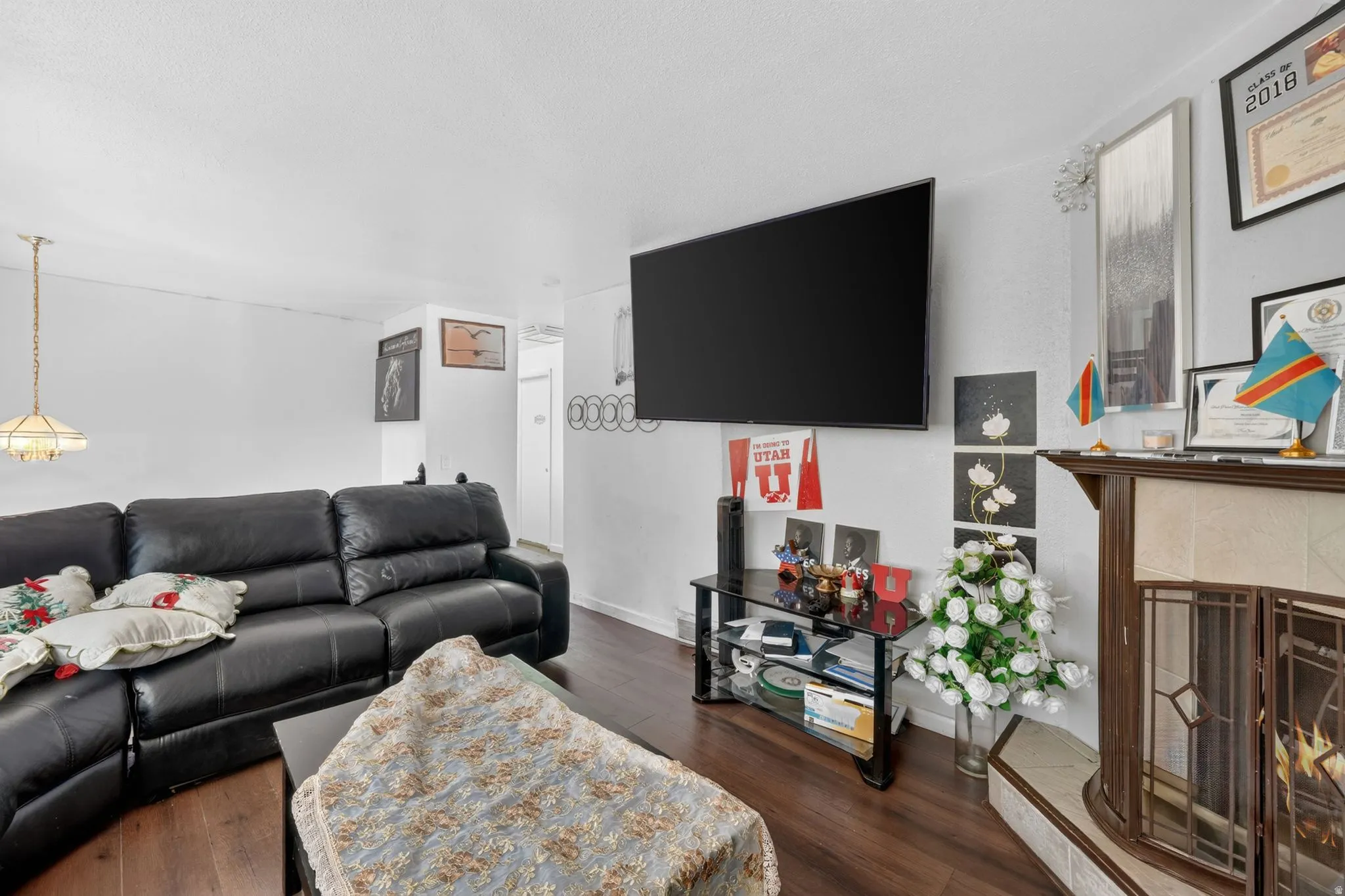 Living area featuring wood-finish flooring and a corner fireplace with a decorative wood mantel