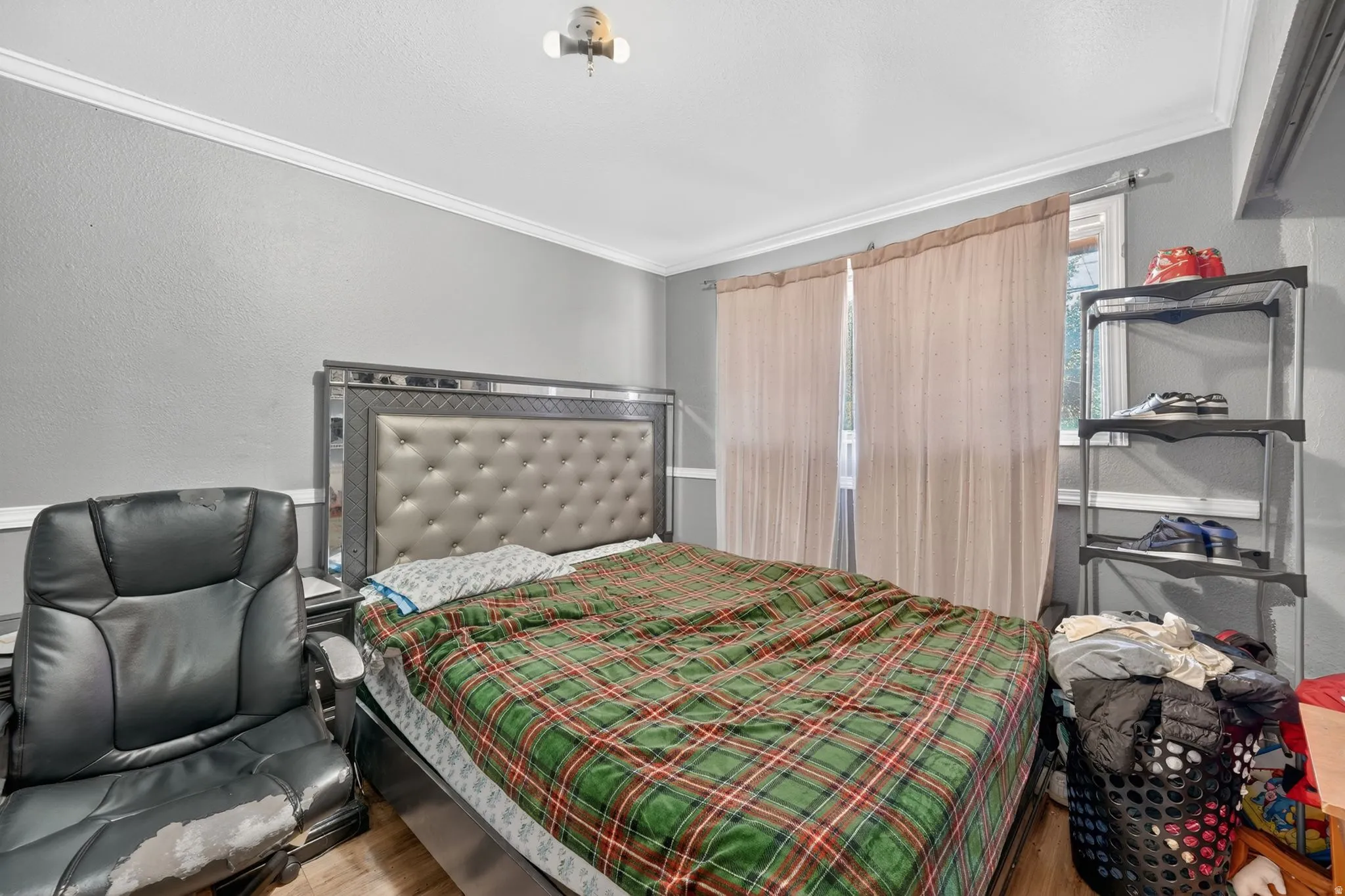 Bedroom featuring light gray walls, white crown molding, and wood-finish flooring