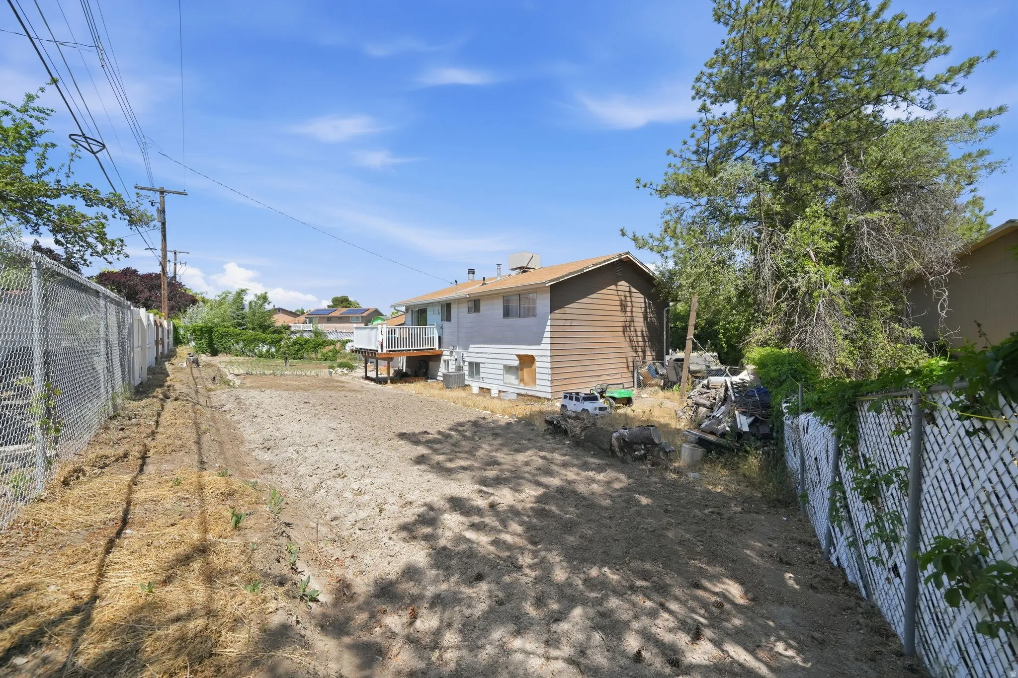 Expansive rear yard with a chain-link fence boundary and established mature trees