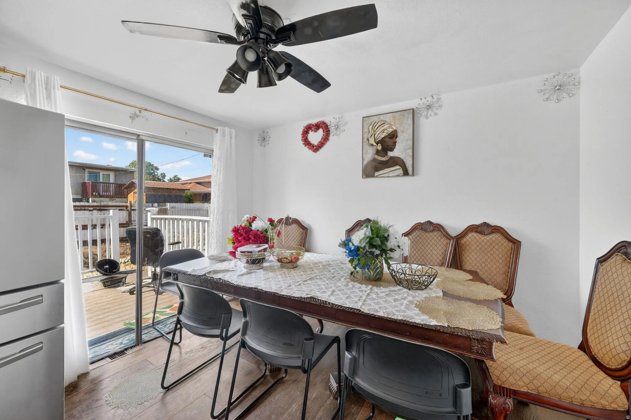 Dining space featuring wood-finish flooring, a ceiling fan, and sliding glass doors opening to an outdoor deck