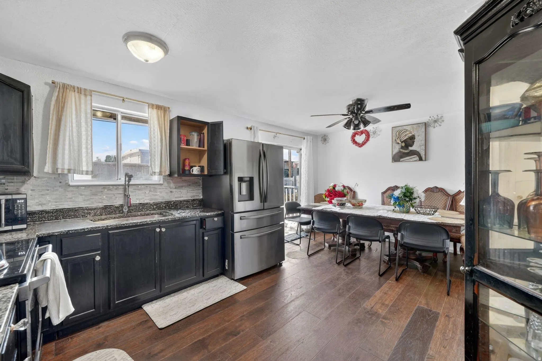 Open-concept kitchen and dining area featuring dark wood-finish flooring, dark cabinetry, and stainless steel appliances
