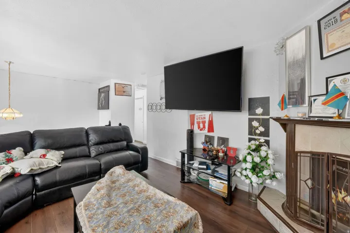 Living area featuring wood-finish flooring and a corner fireplace with a decorative wood mantel