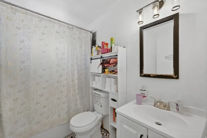 Bathroom featuring a white vanity with an integrated sink, polished chrome faucet, and a wall-mounted mirror with an overhead three-light fixture