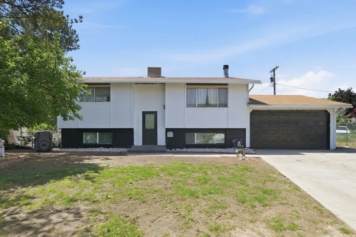 Two-story residence featuring a two-tone exterior, a prominent garage with a roll-up door, and a concrete driveway